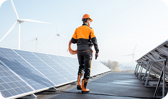 Man wearing an orange helmet working next to solar panels.